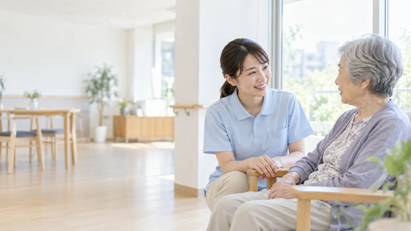 明るい施設で介護スタッフと利用者が話すAI生成イメージ